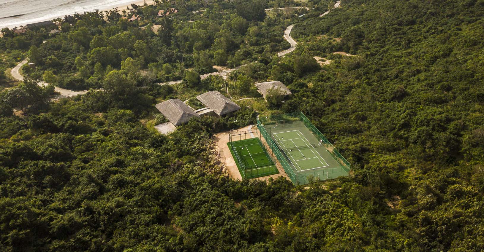 Aerial view of padel courts surrounded by tropical greenery